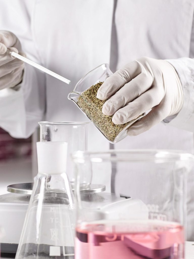 Analyse reliquat azote – Présentation page Biotechnology and pharmacology concept. Laboratory young clever worker standing near table surrounded with glass beakers filled with colorful liquid working at discovering new kind of vegetation.
